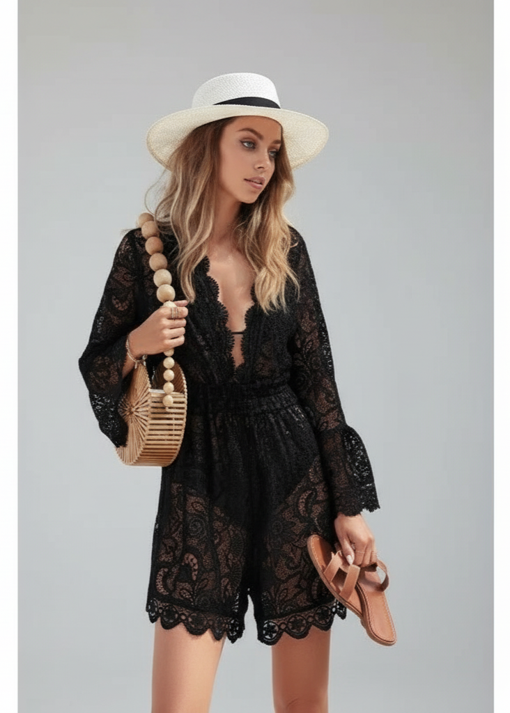 Woman wearing a black lace romper with a white hat and holding a beige bag on a gray background