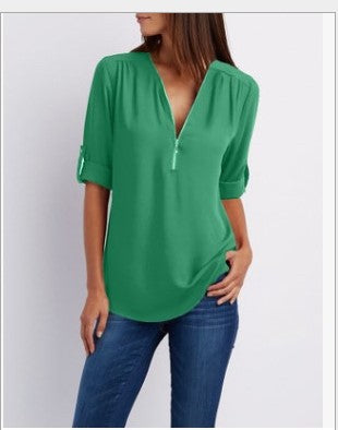 Person wearing a green blouse with a V-neck and short sleeves on a white background
