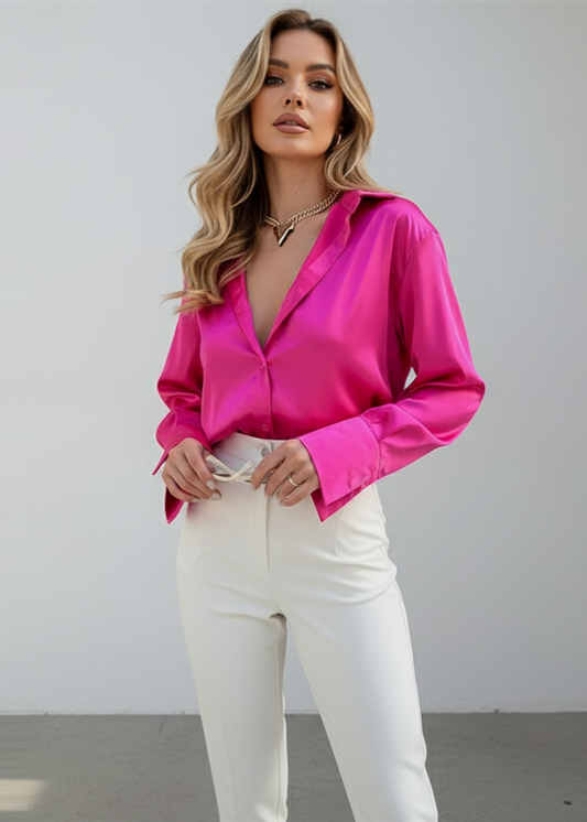 Woman wearing a bright pink blouse and white pants against a plain background