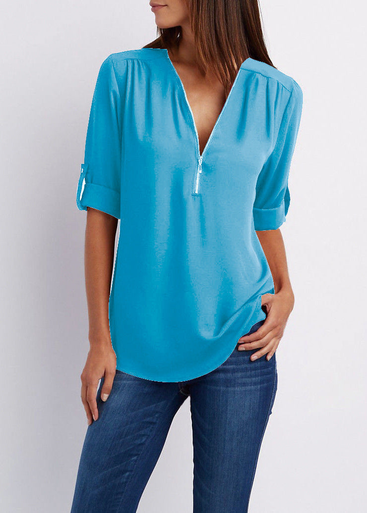 Woman wearing a blue blouse with a deep neckline on a plain background
