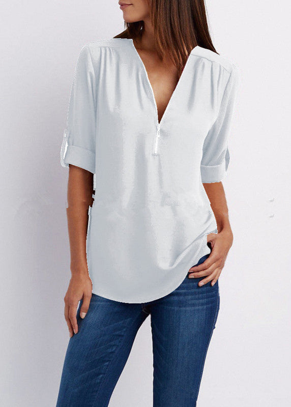 Woman wearing a white blouse and blue jeans on a plain background