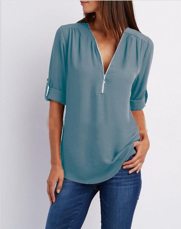 Teal blouse worn by a person on a white background