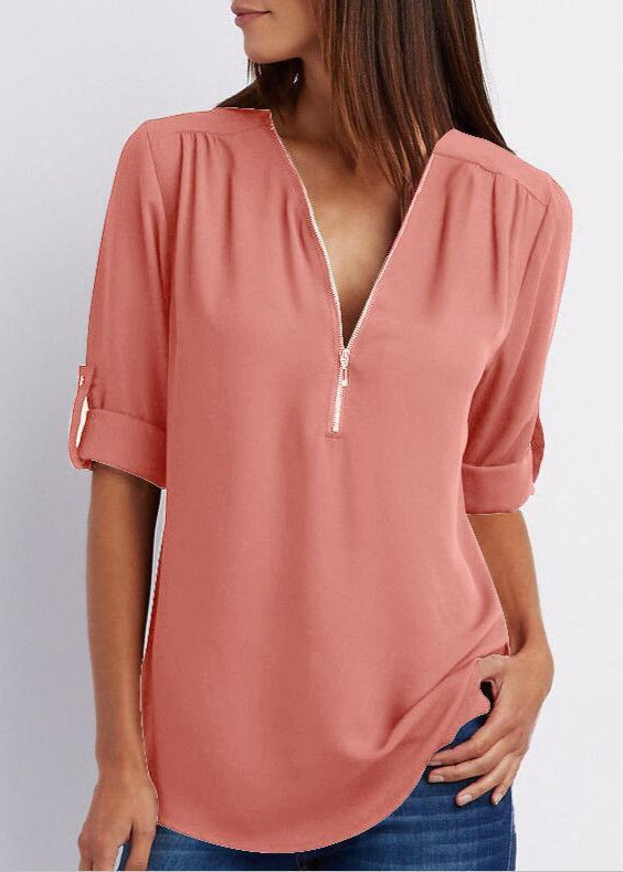 Woman wearing a pink blouse with a zipper detail on a plain background