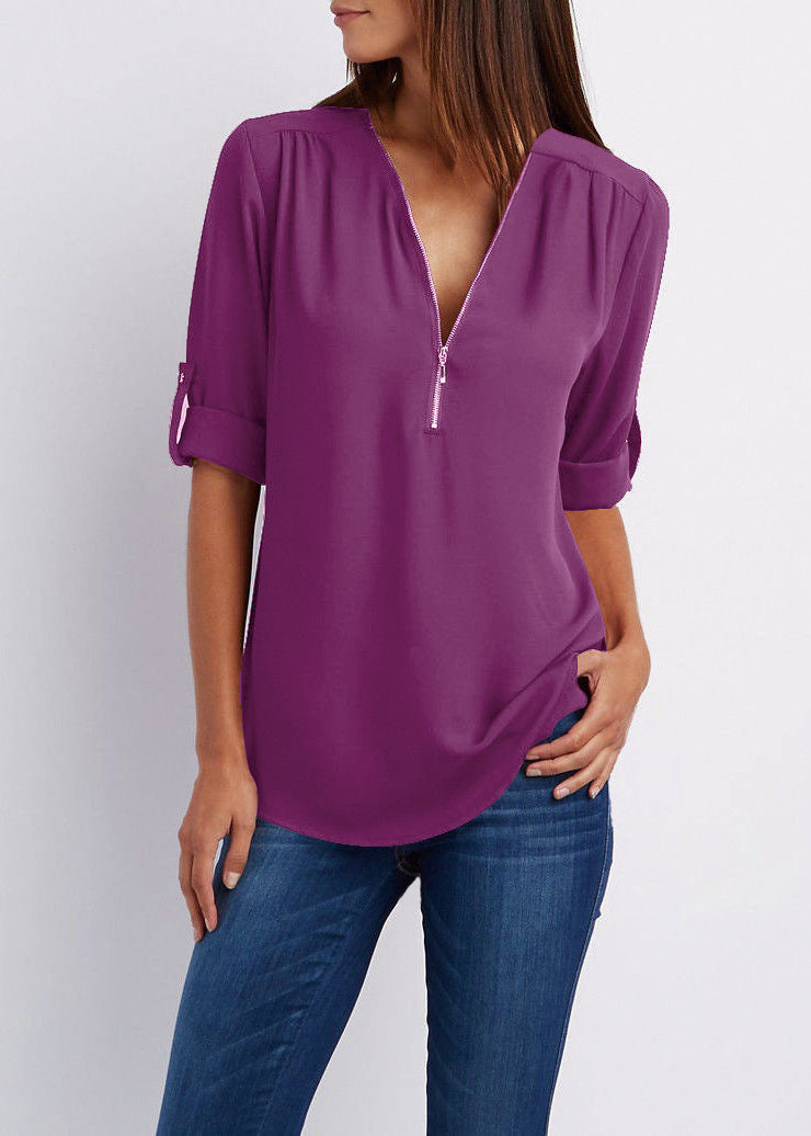 Purple blouse with a deep neckline worn by a person on a plain background