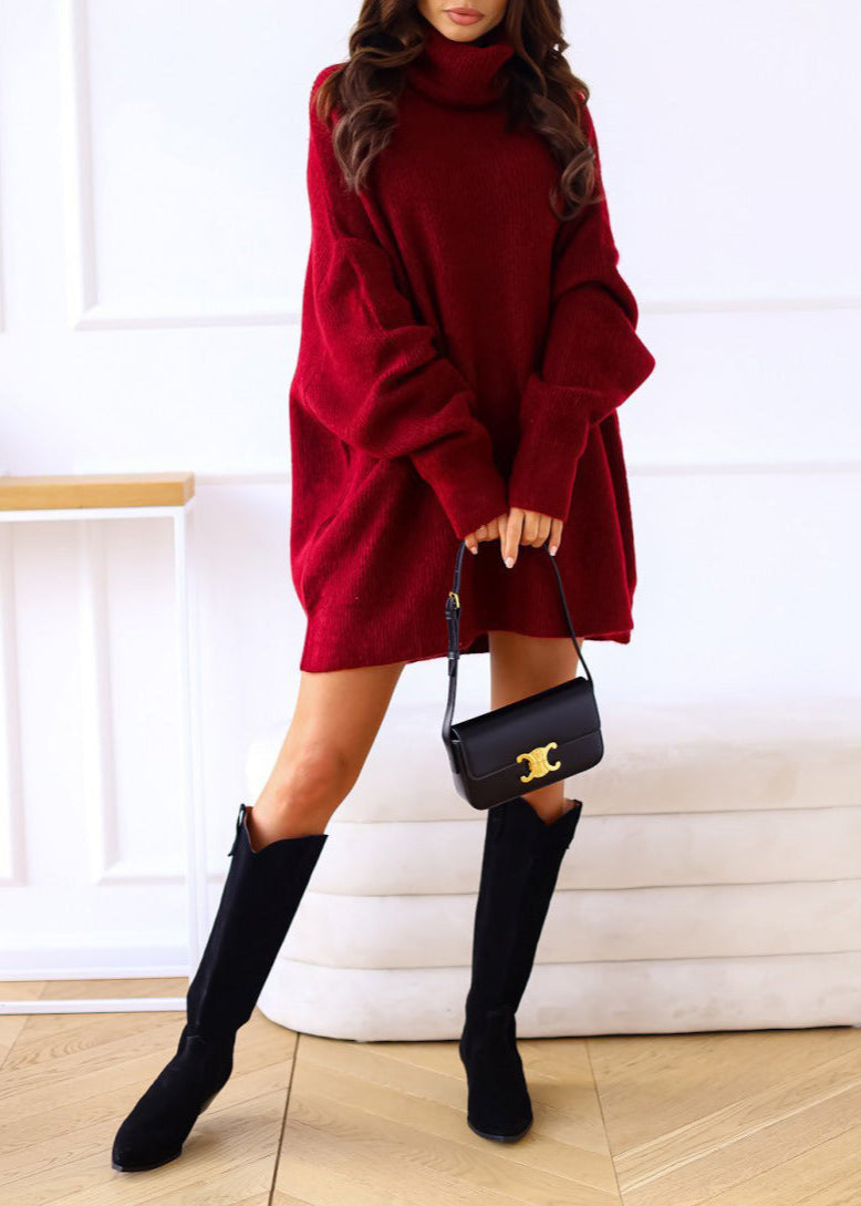 Person wearing a red sweater dress and black knee-high boots, holding a black handbag with a gold chain.