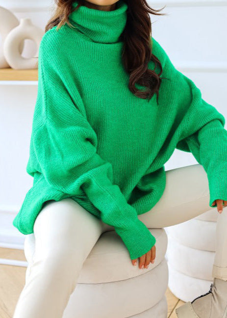 Person wearing a green sweater sitting on a white chair.