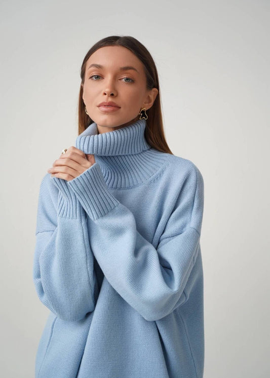 Woman wearing a light blue turtleneck sweater against a plain background