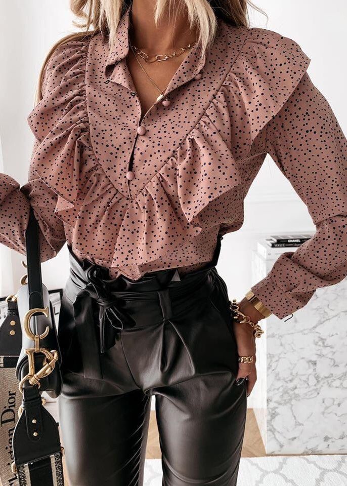 Person wearing a pink polka dot blouse and black leather pants with a Dior handbag.