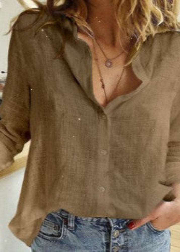 Person wearing a brown button-up shirt and blue jeans indoors.