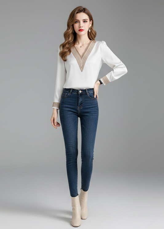 Woman wearing a white blouse with a V-neck and blue jeans on a gray background